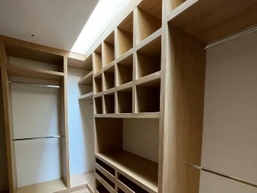 Vestidor a la medida en chapa de roble con entrepaños abiertos, cajonera y barra de colgado