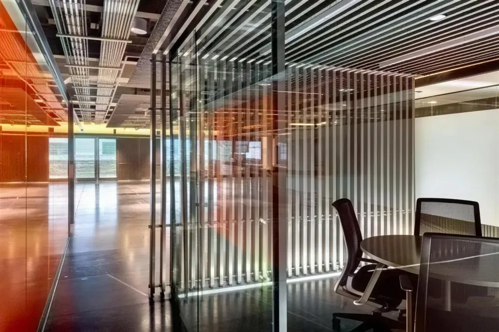Oficinas con muro de listones metálicos verticales, cristal y salas de juntas