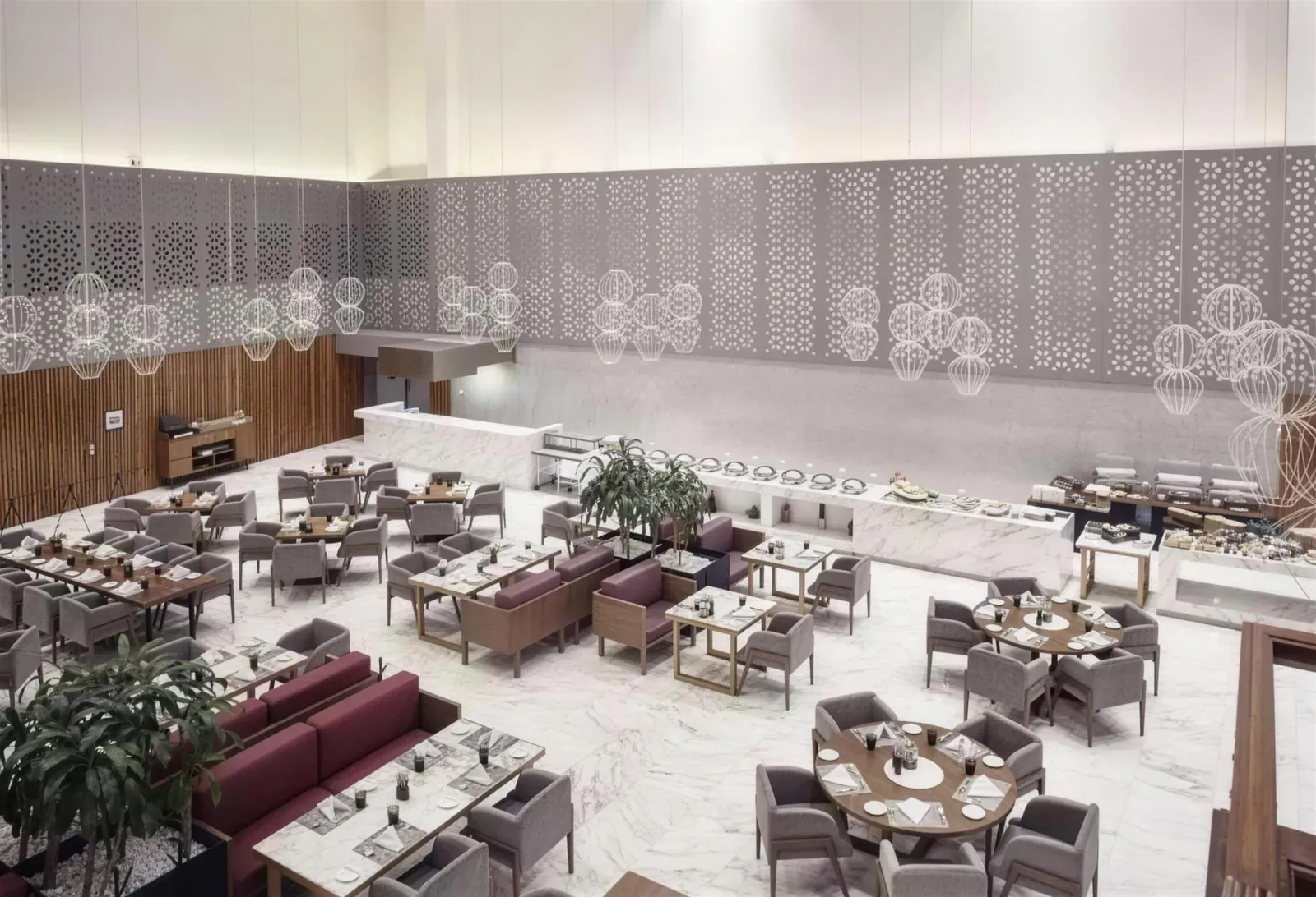 Restaurante del hotel con muro perforado, mesas y mobiliario en madera y mármol blanco, visto desde arriba