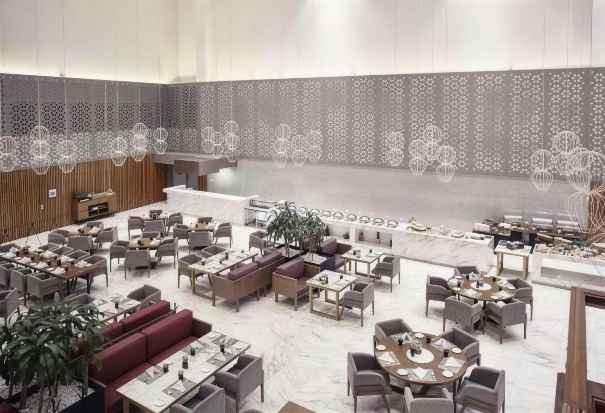 Salón de restaurante de doble altura con piso de mármol, celosías caladas en los muros, lámparas colgantes esféricas y mobiliario en gris y vino