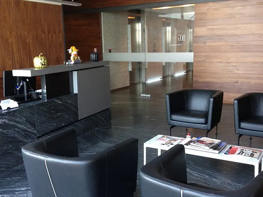 Recepción corporativa con piso de granito, recubrimientos de madera y mobiliario fijo